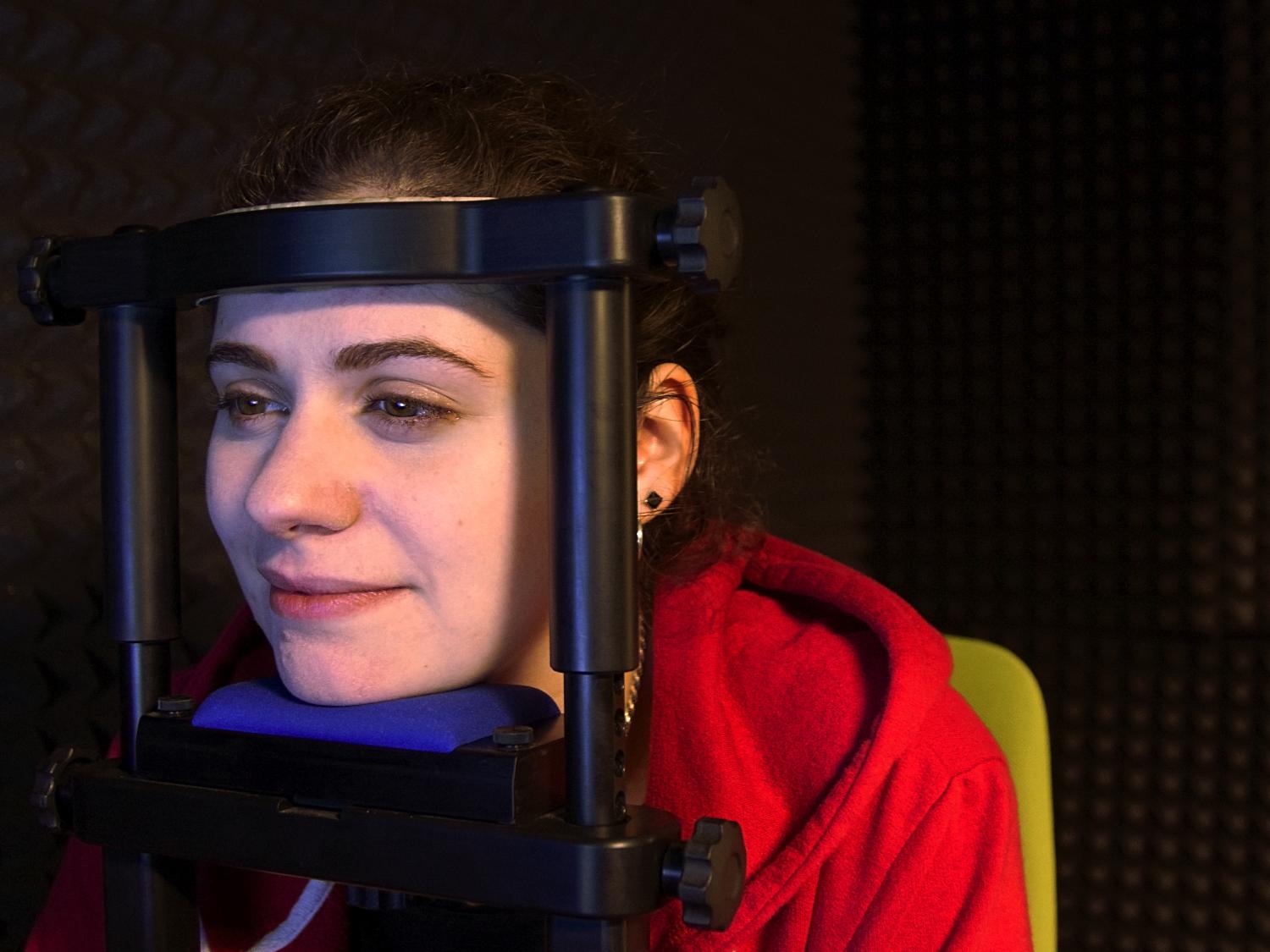 A student sits with their head in the chin rest of the eye-tracking device. 
