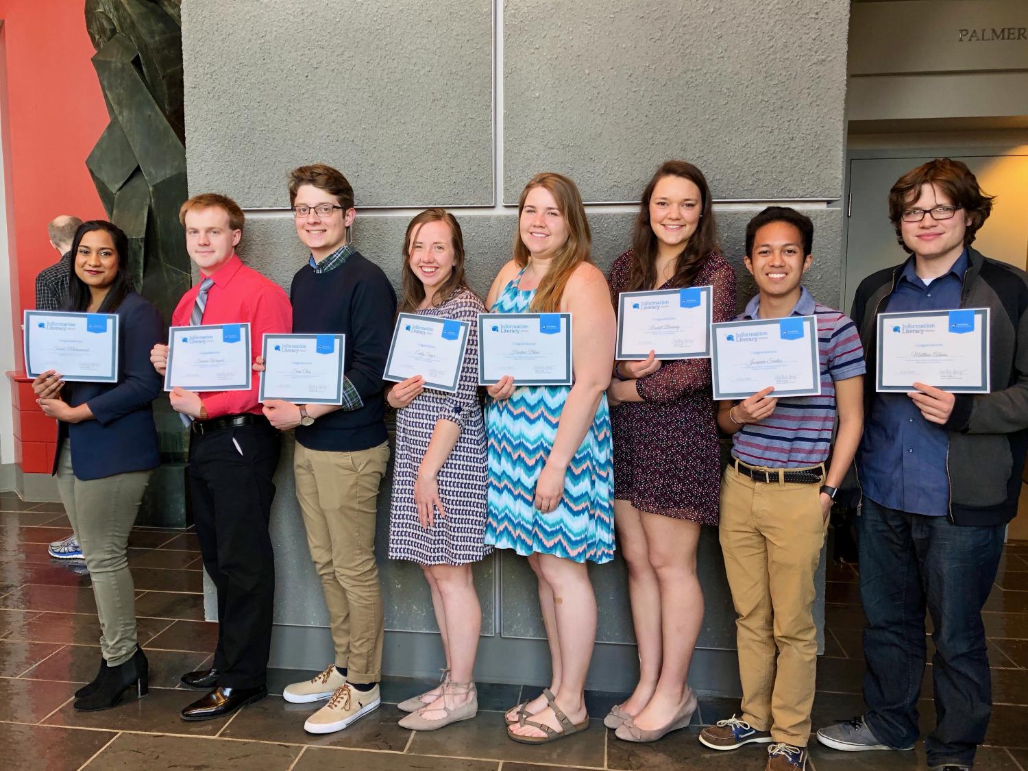 photo of eight students standing in a line and holding certificates 