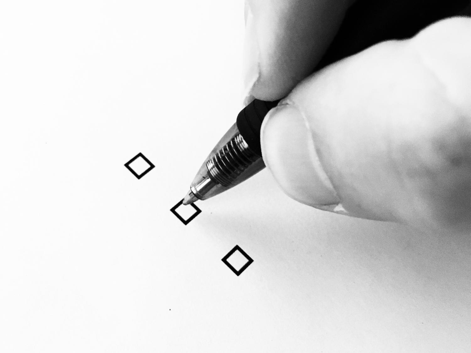 A person holding a pen, preparing to check a box on a piece of paper.