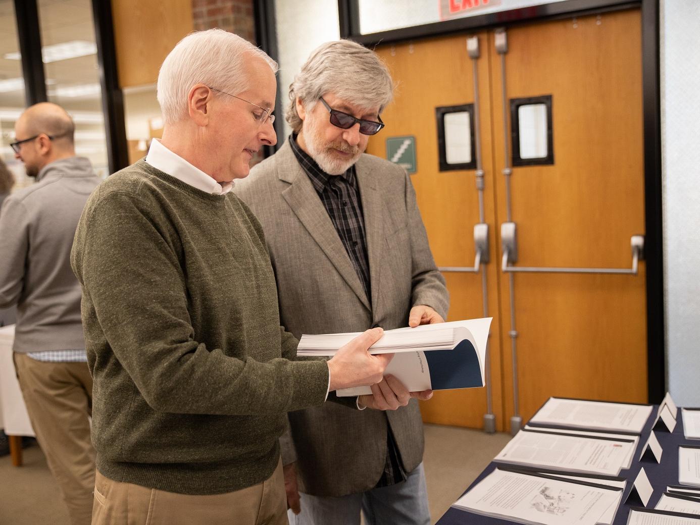 Dr. Harnish and Dr. Bridges stand while looking at book