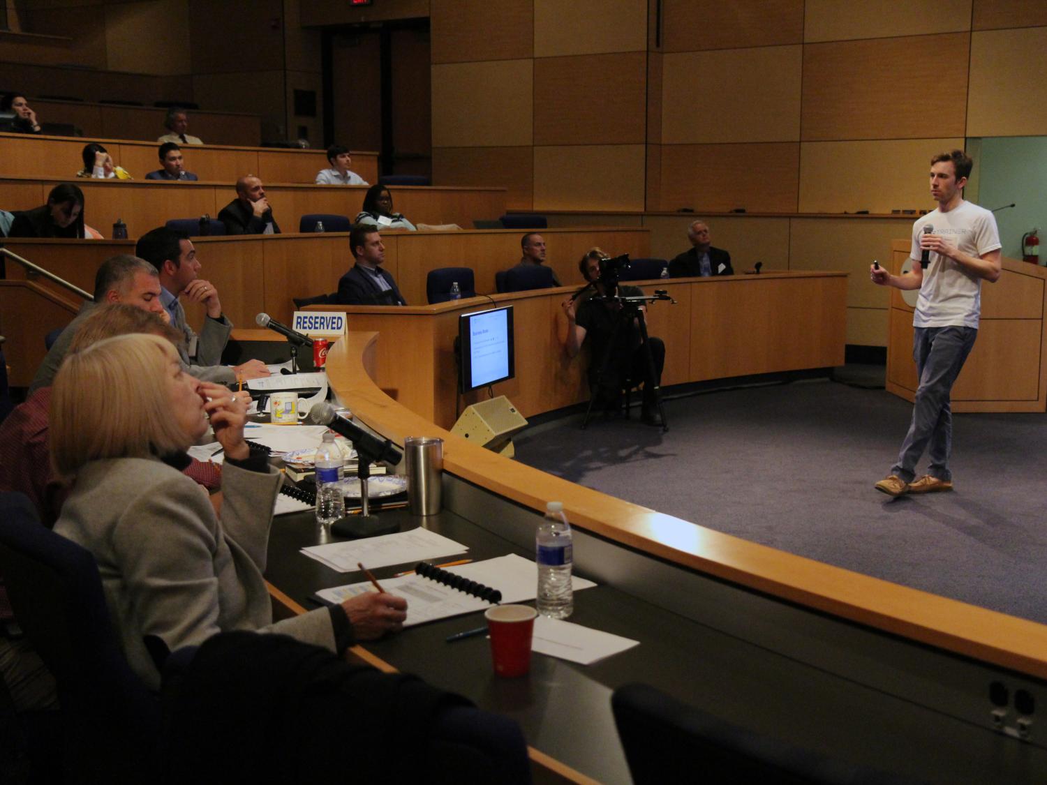 Student presenting business idea to panel of judges in auditorium