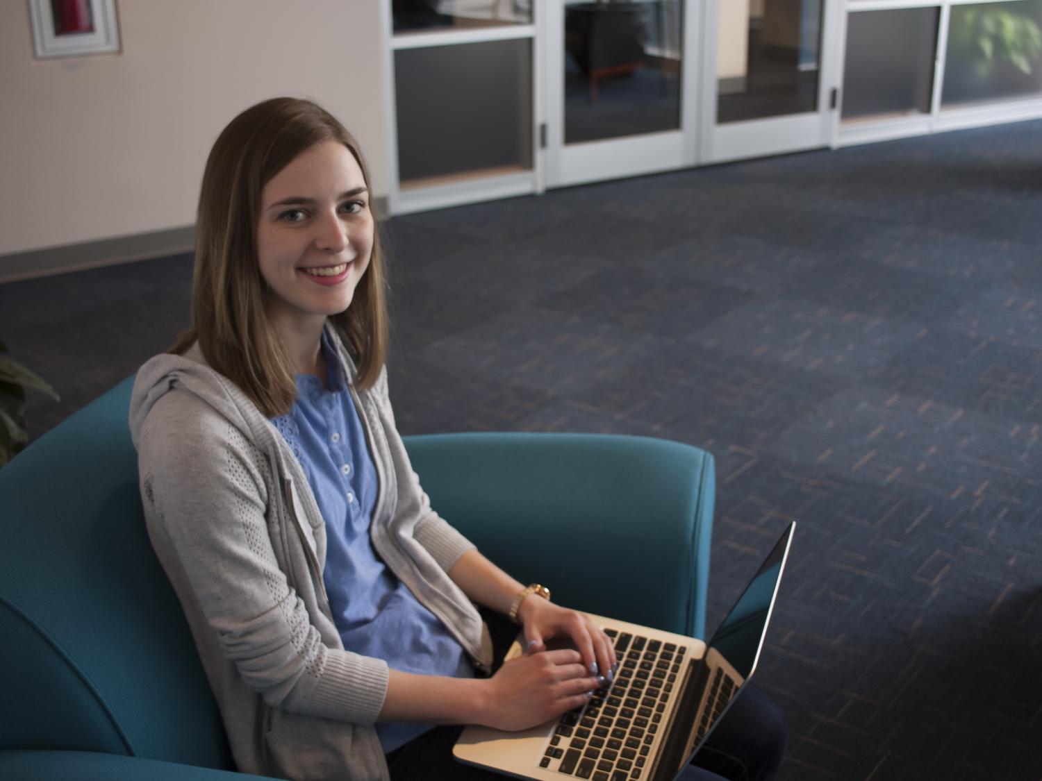 Audra Stafursky smiles at the camera while working on her computer