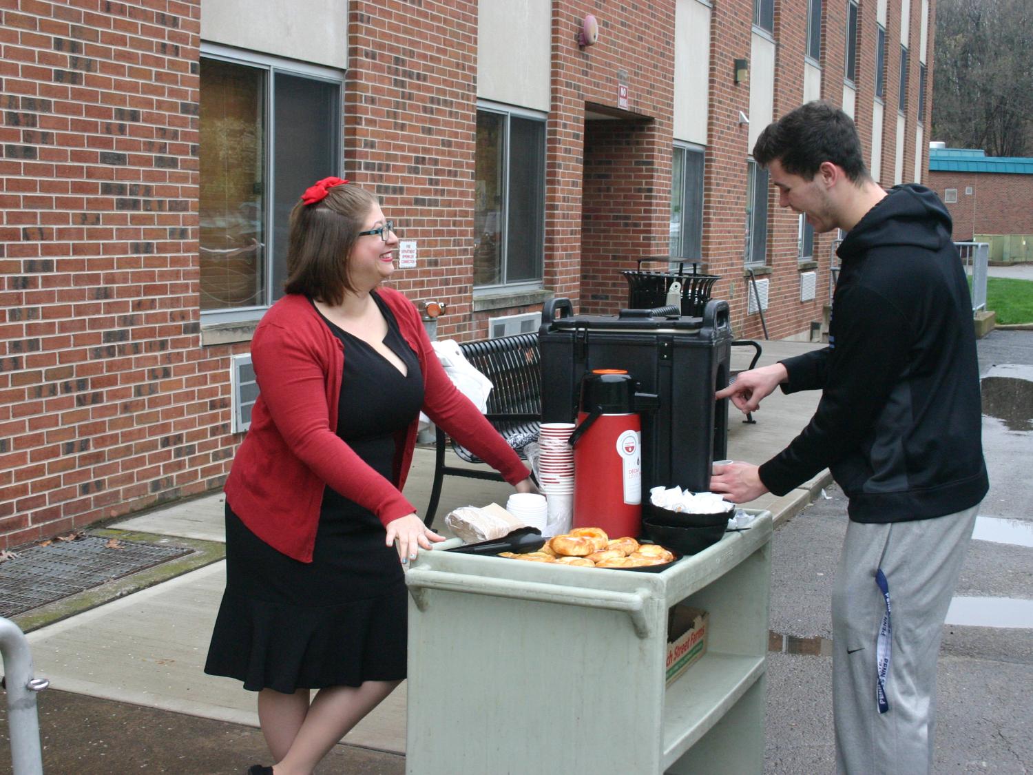 Associate Director of Student Services and Engagement Devon Purington serves coffee and danish to a student outside the residence halls at Penn State Hazleton.