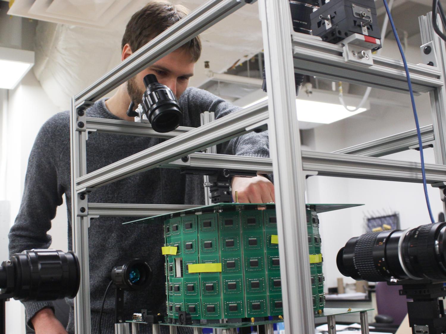 A Caucasian man stands in front of a tabletop virtual reality simulator for flying insects. 