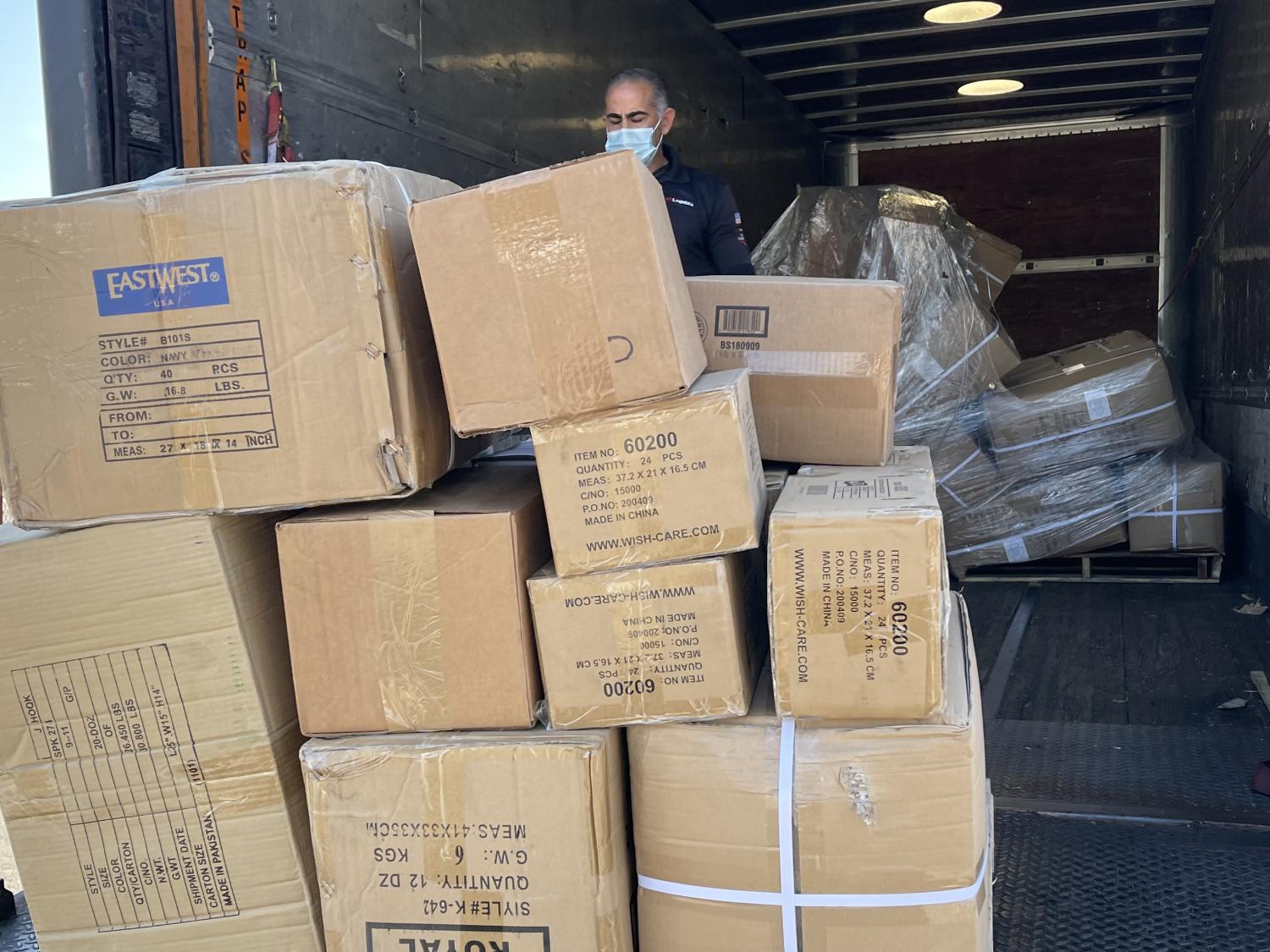 A person in a moving truck moves a pallet loaded with cardboard boxes down the truck ramp.