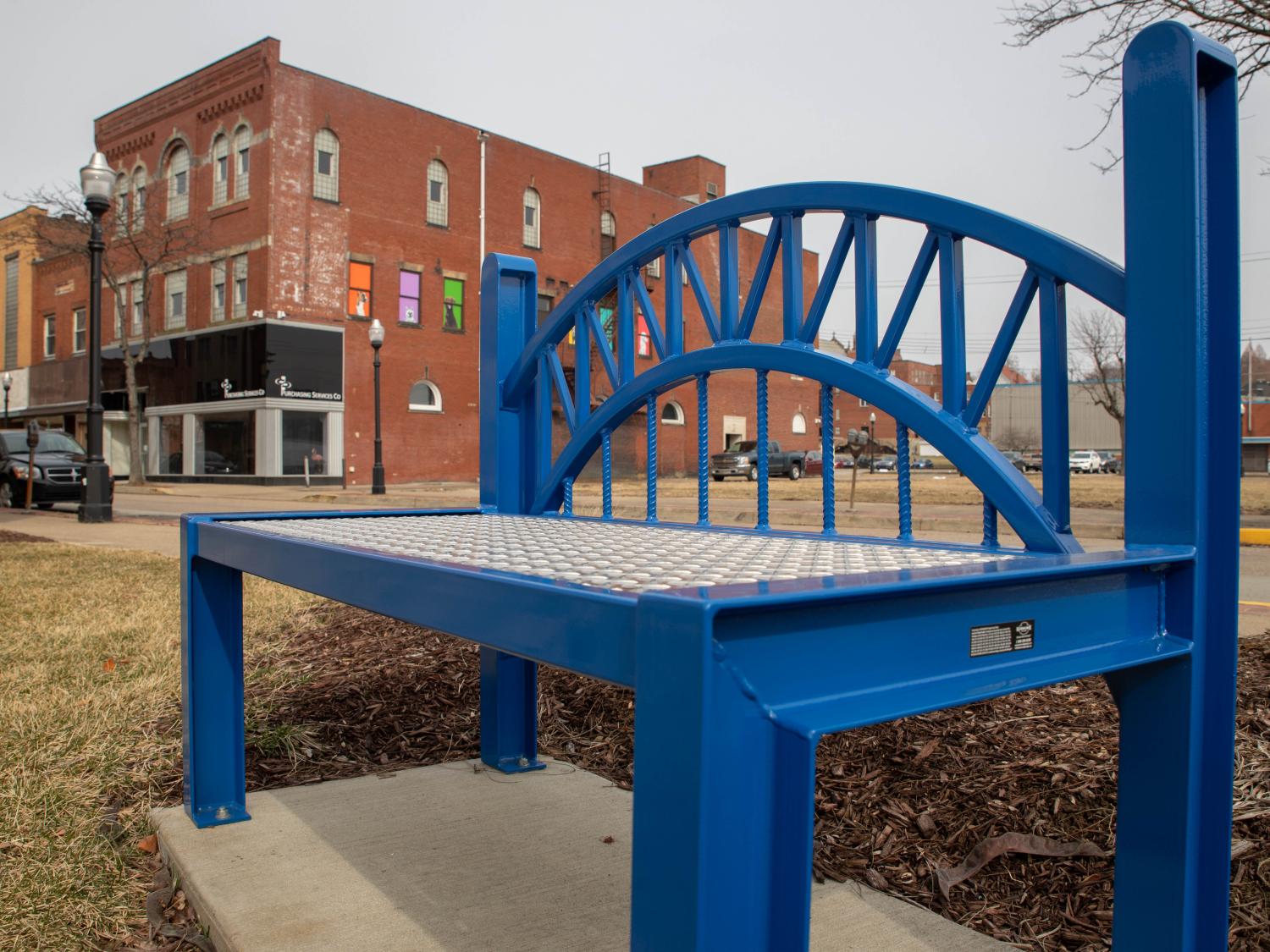 A blue bench along the sidewalk in New Kensington