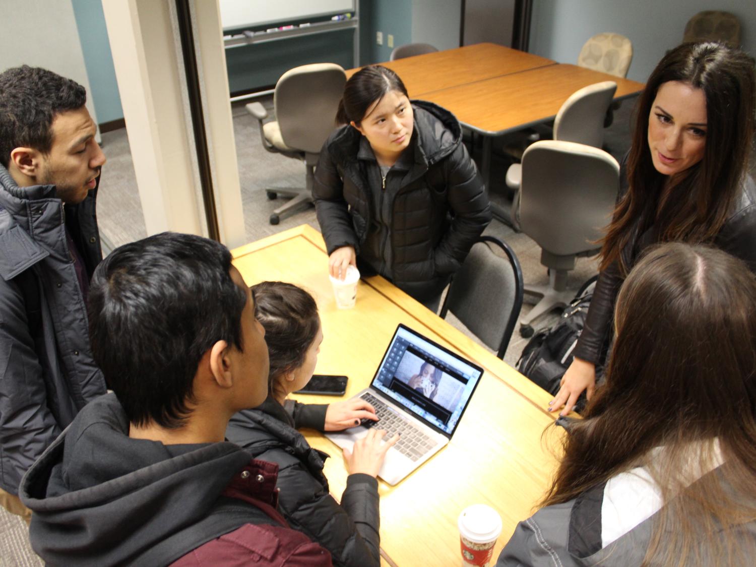 Six people gathered around a desk to talk