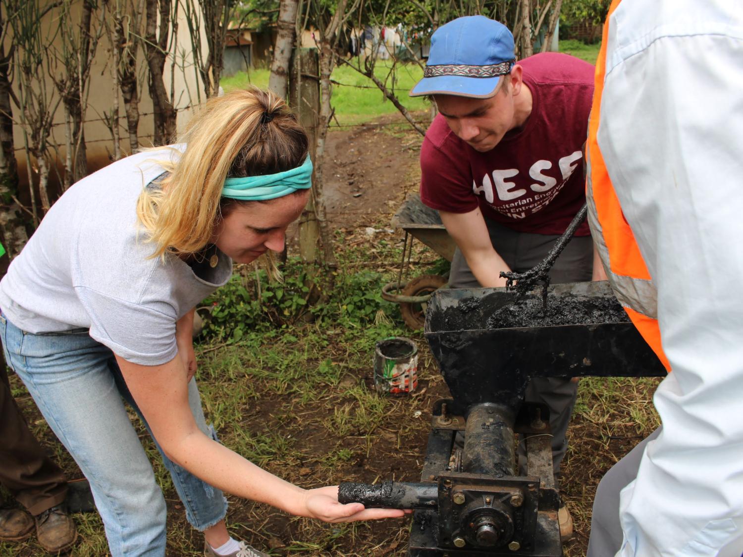 Female student holds fuel brick being made