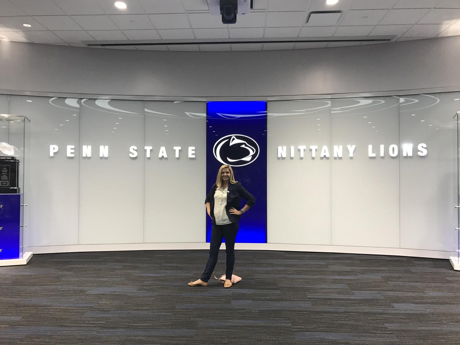 Woman standing in front of a wall with the Penn State athletics symbol and the wording "Penn State Nittany Lions."
