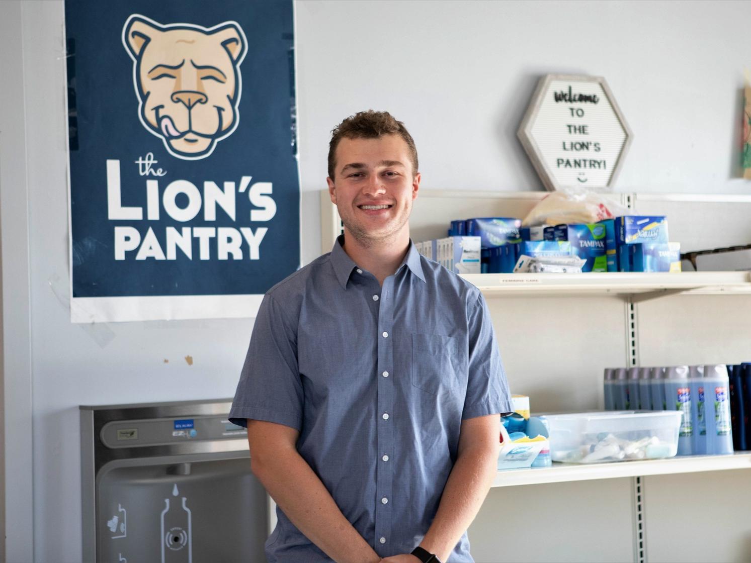 Spencer Wallace stands in front of the Lion's Pantry banner