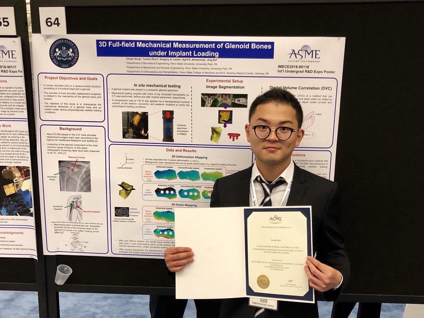 Chulie Gong posing with his award in front of his poster