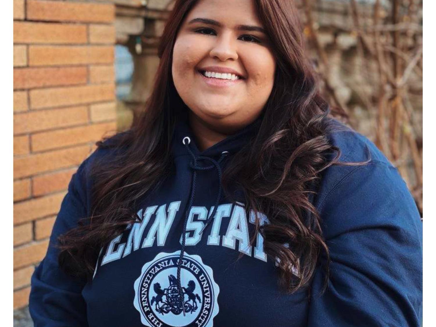 Zeenat Chughtai wearing a Penn State sweatshirt and smiling outside