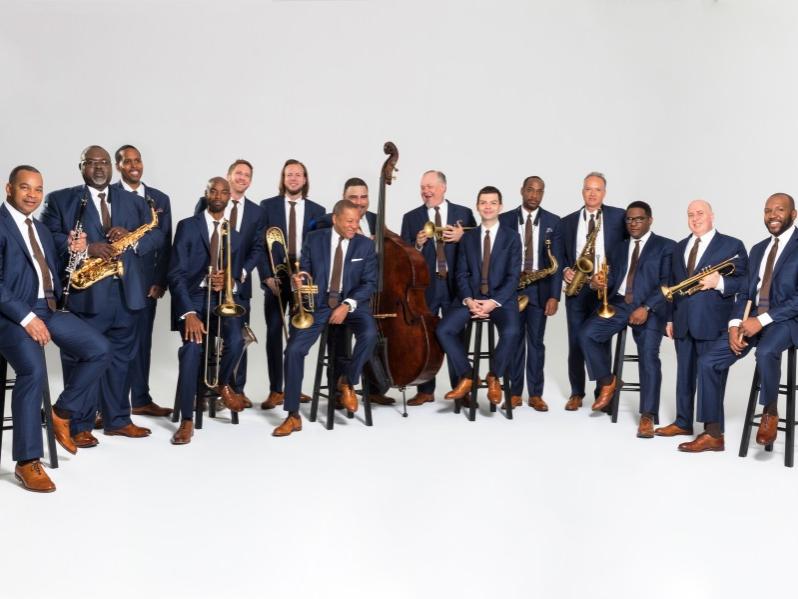 A group of musicians stand in a row and hold their instruments.