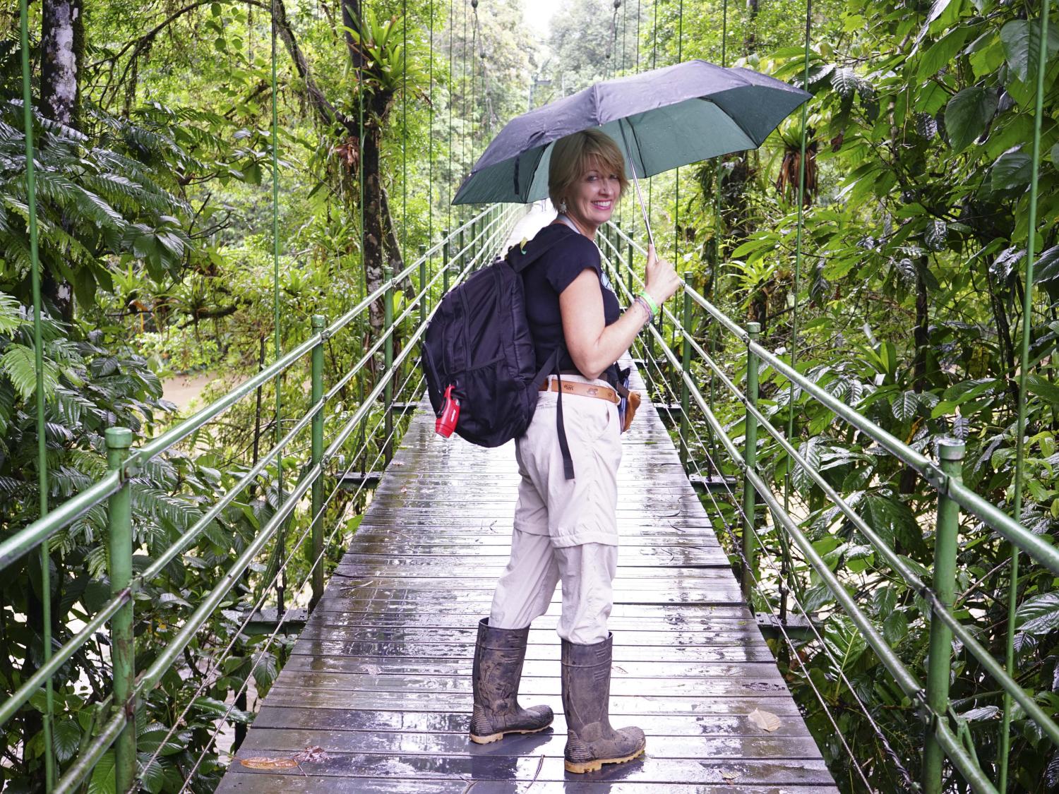 Professor McLaughlin stands with an umbrella on a bridge in Costa Rica.