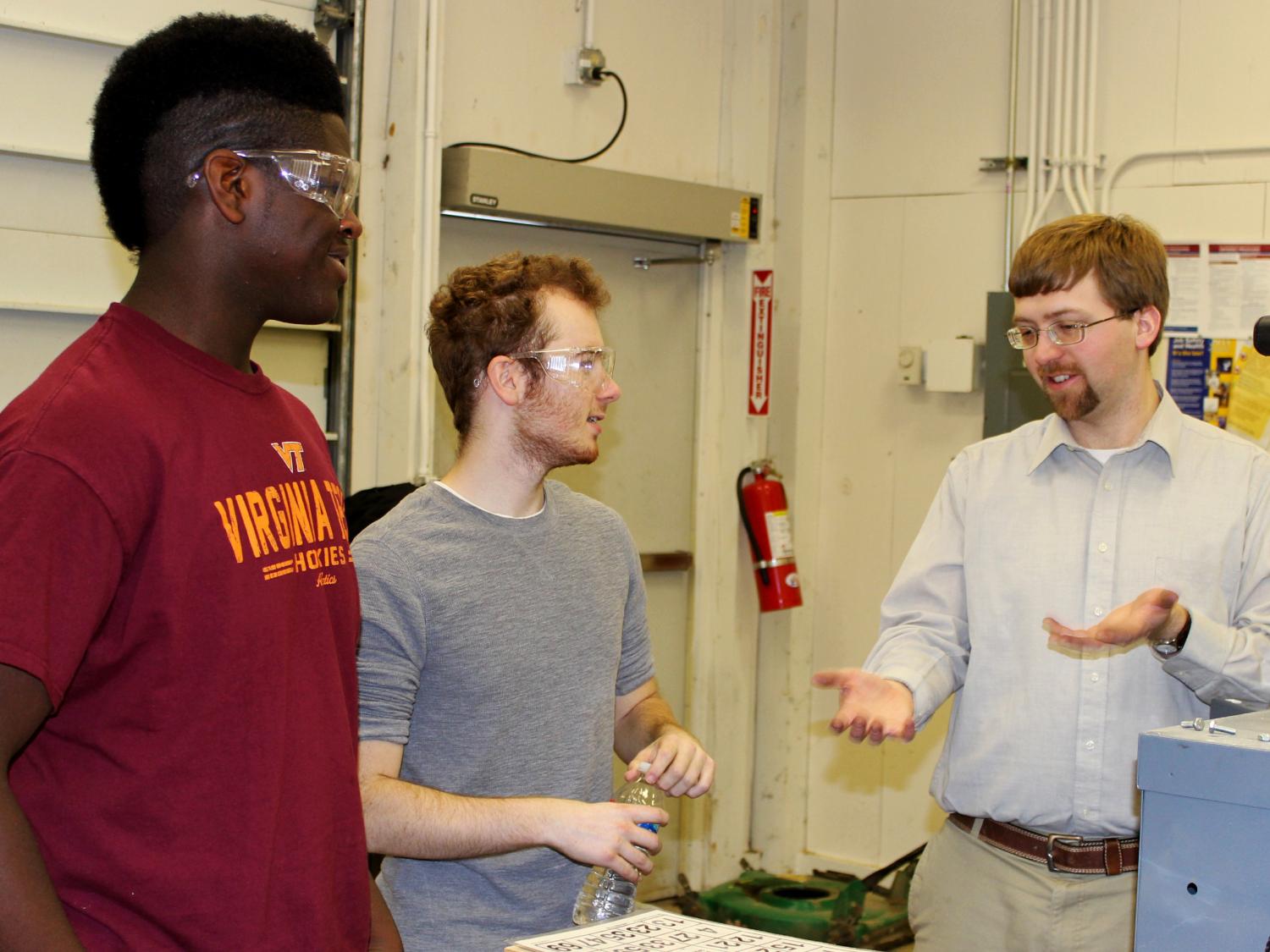 Two students work with Jacob Moore in a lab. 