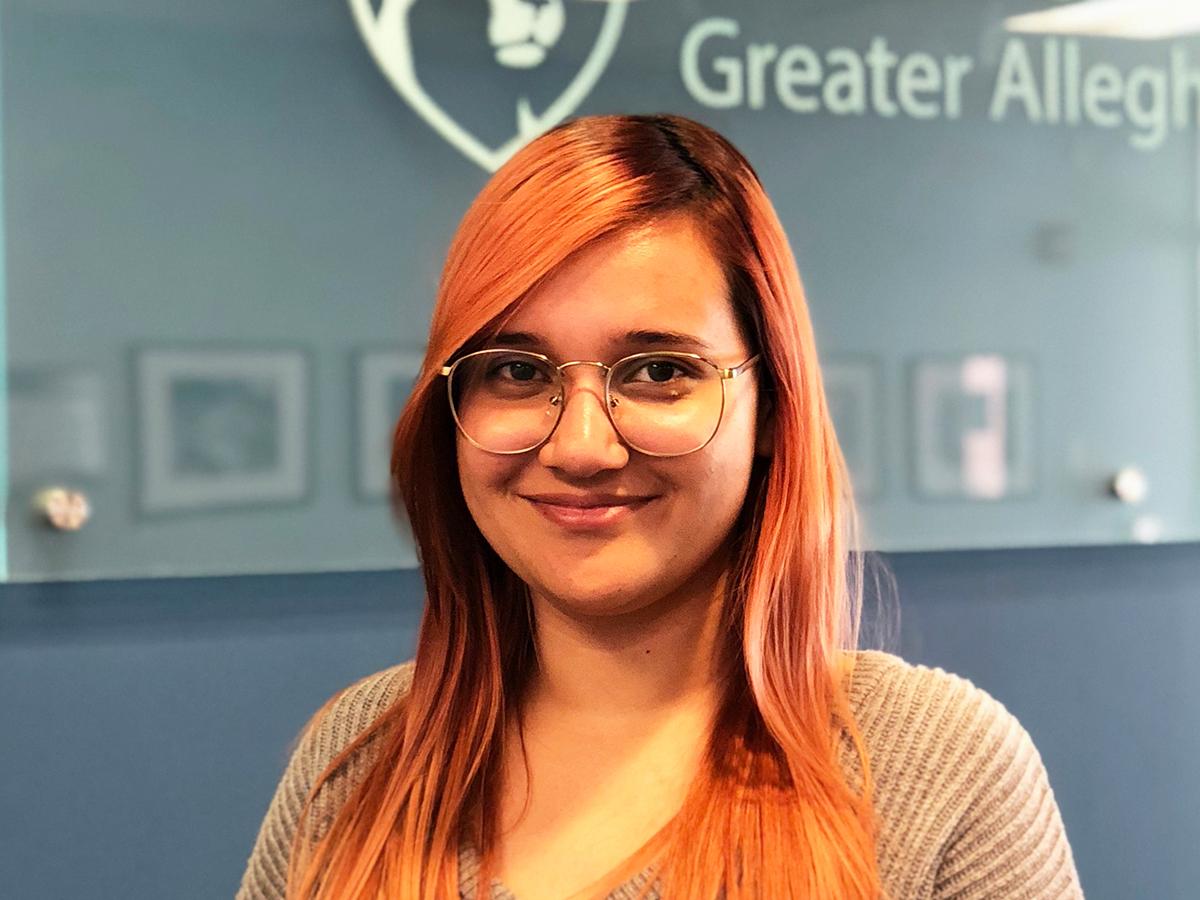 Student Yadeiliz Mari smiling standing in front of Penn State Greater Allegheny Logo