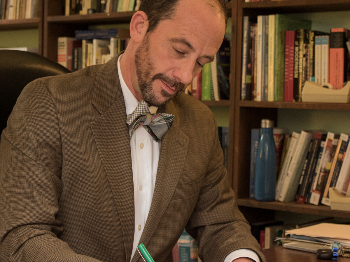 James Jaap reads Willa Cather in his office in front of book shelf