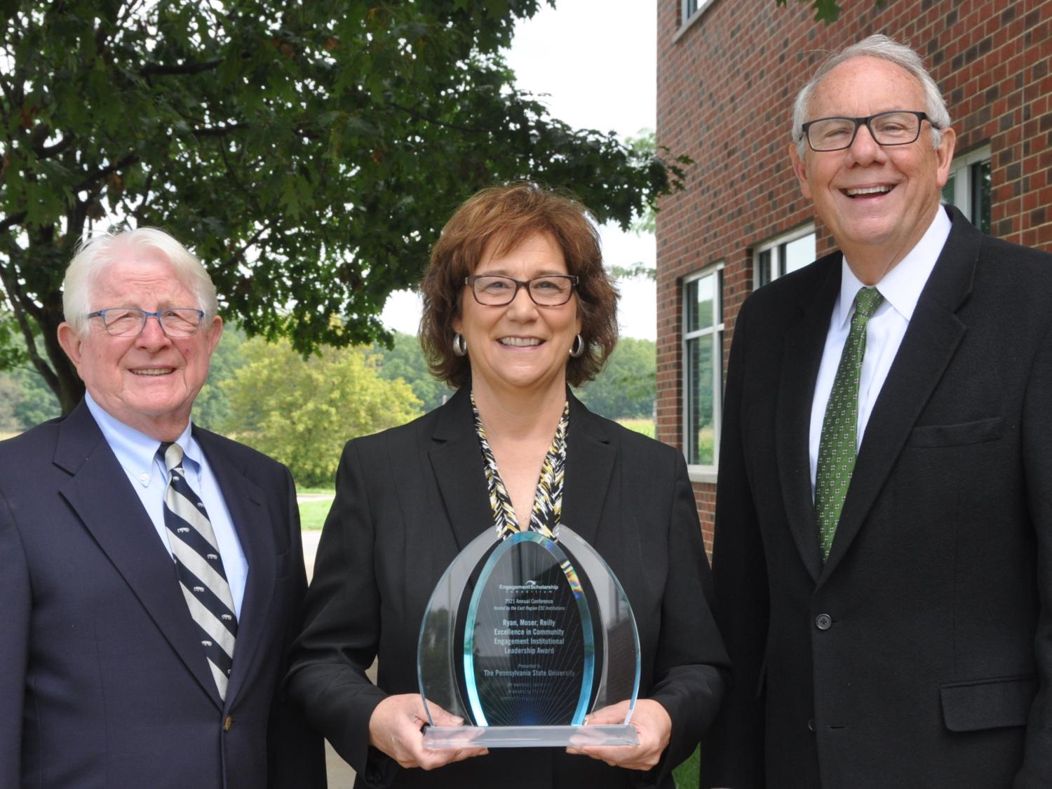 Portrait of award winners holding a plaque