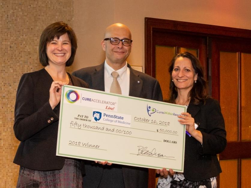 Dr. John Elfar, center, receives a check from Clare Thibodeaux, director of scientific affairs, Cures Within Reach, and Barbara Goodman, president and COO, Cures Within Reach.