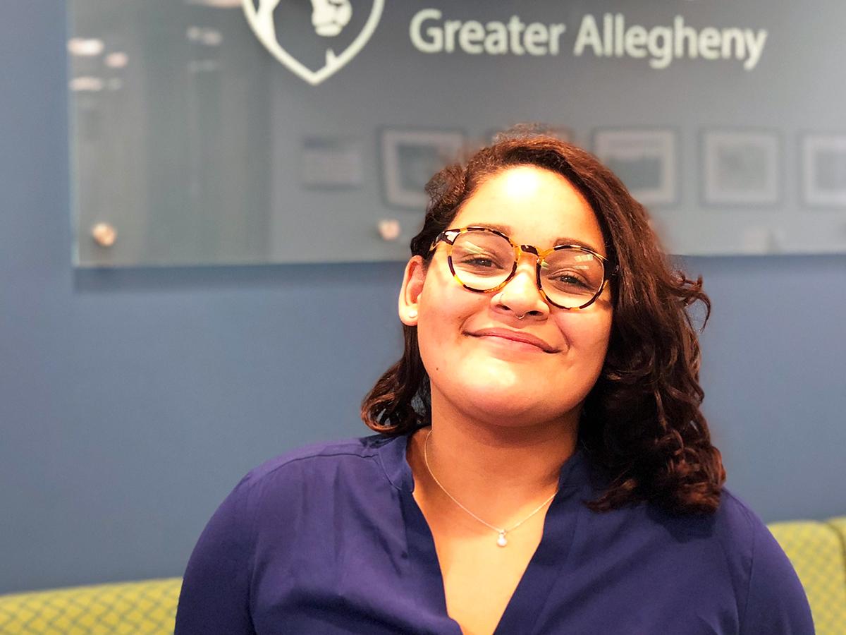 Exchange Student Joyce Cabrera smiling in front of Penn State Greater Allegheny log 