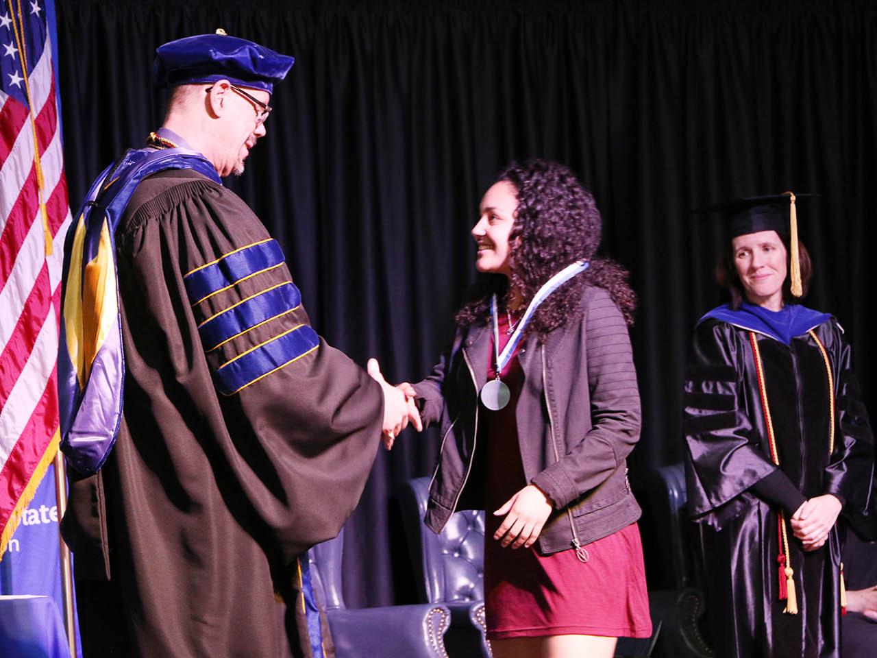 Student receives medal from chancellor at Academic Achievement Awards ceremony. 