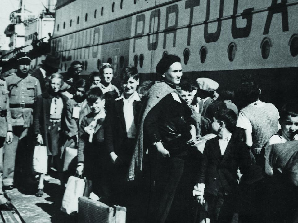 black and white photo of people waiting to board a boat