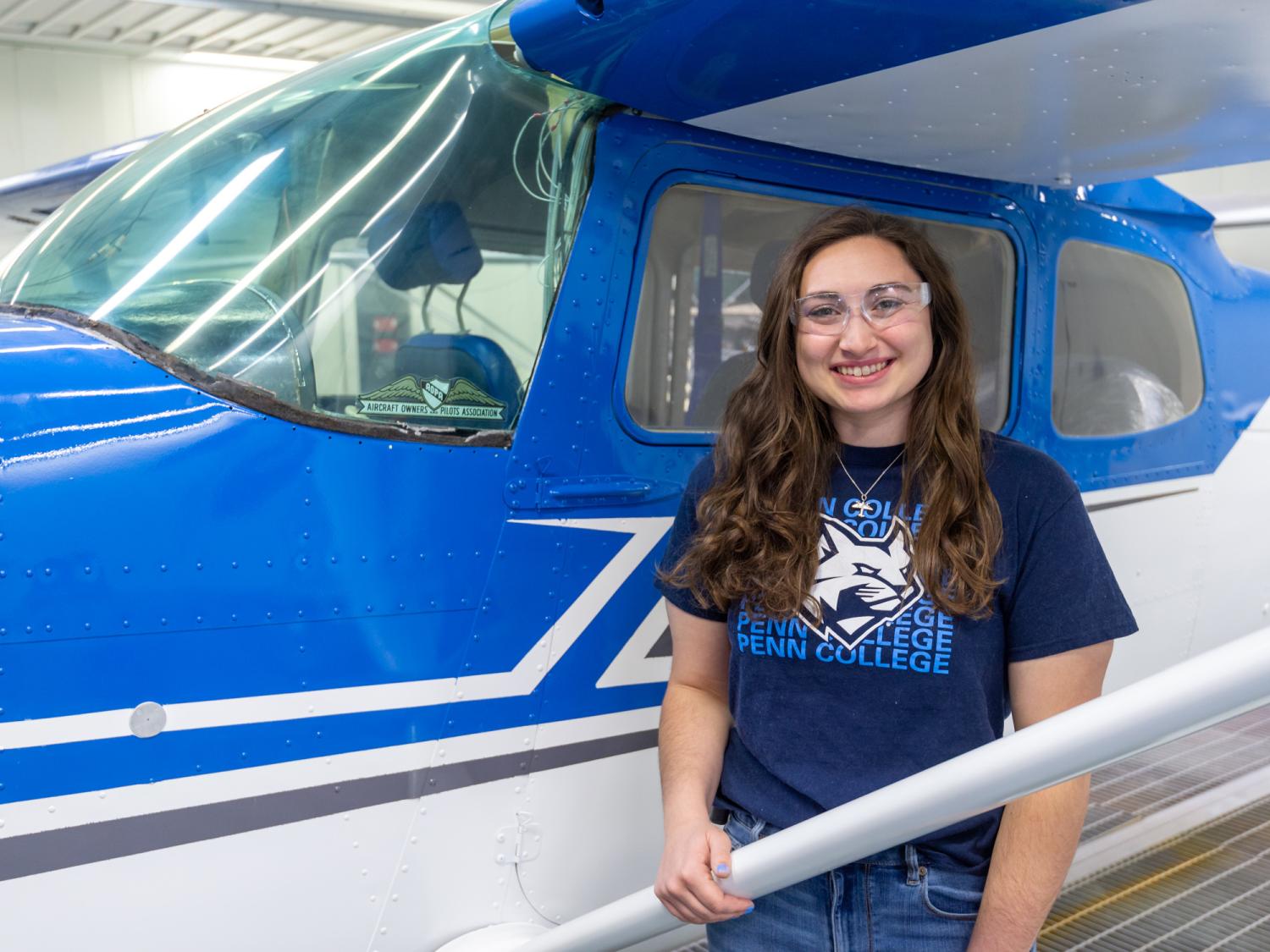 Kate Ruggiero stands alongside a blue and white Cessna airplane