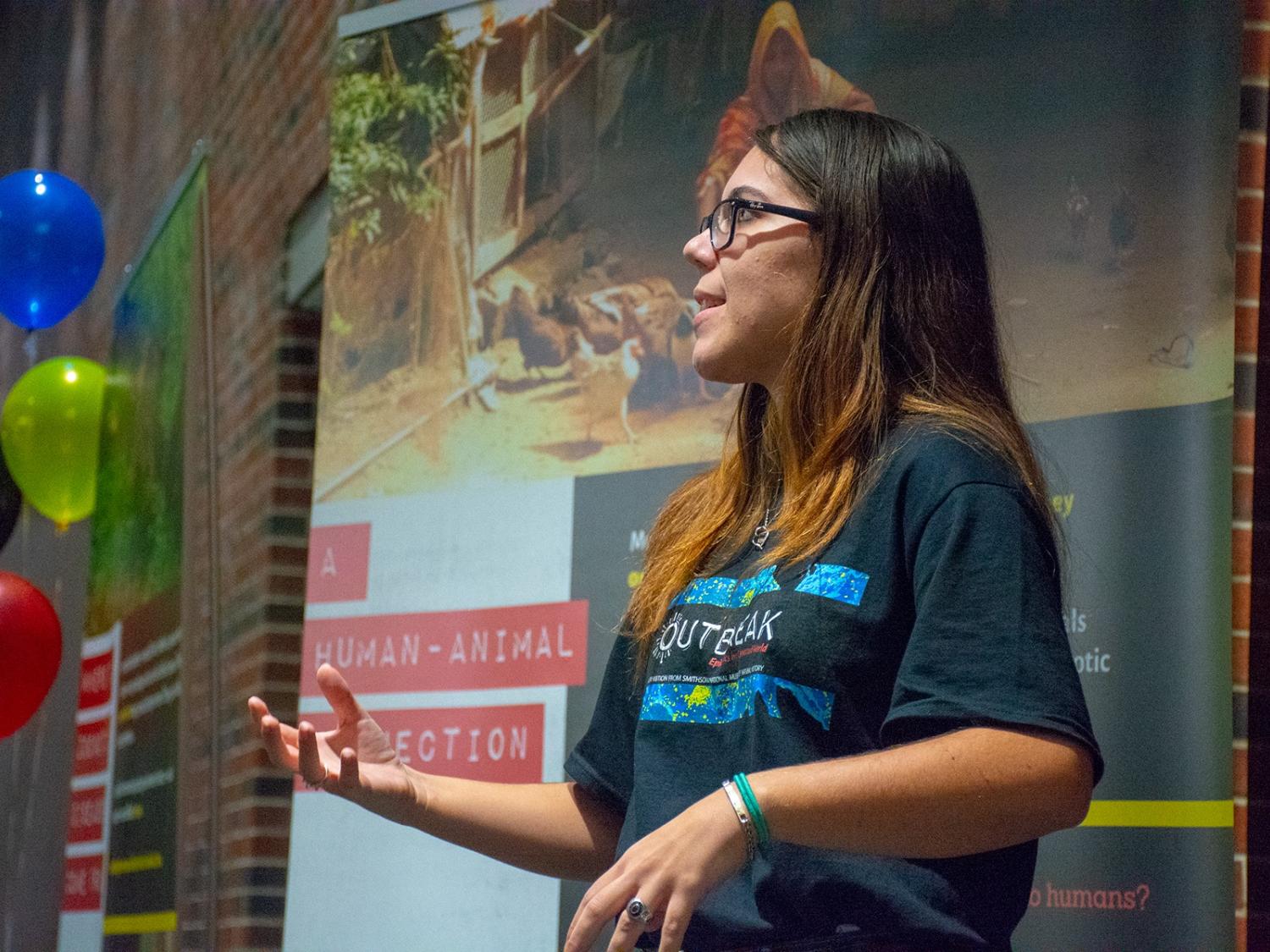 Alumna Katie Alemany addresses the crowd in her role as volunteer exhibit tour guide