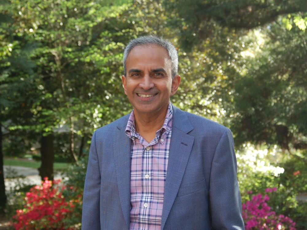 Dr. Krish Sathian poses for a photo outdoors. Trees are in the background.