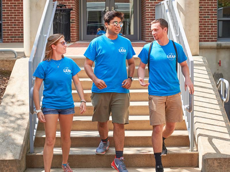 Three LEAP mentors in matching blue tee-shirts walk out of Bank of America Building