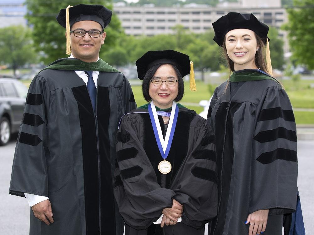From left: Dr. Peter Zaki, Dr. Shou Ling Leong and Dr. Sarah Stovar pose for a photo, each wearing a cap and gown..