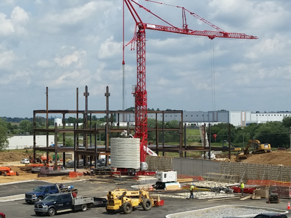 A crane erects steel beams at a hospital construction site