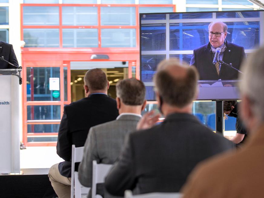 A small crowd watches a man speak at a podium