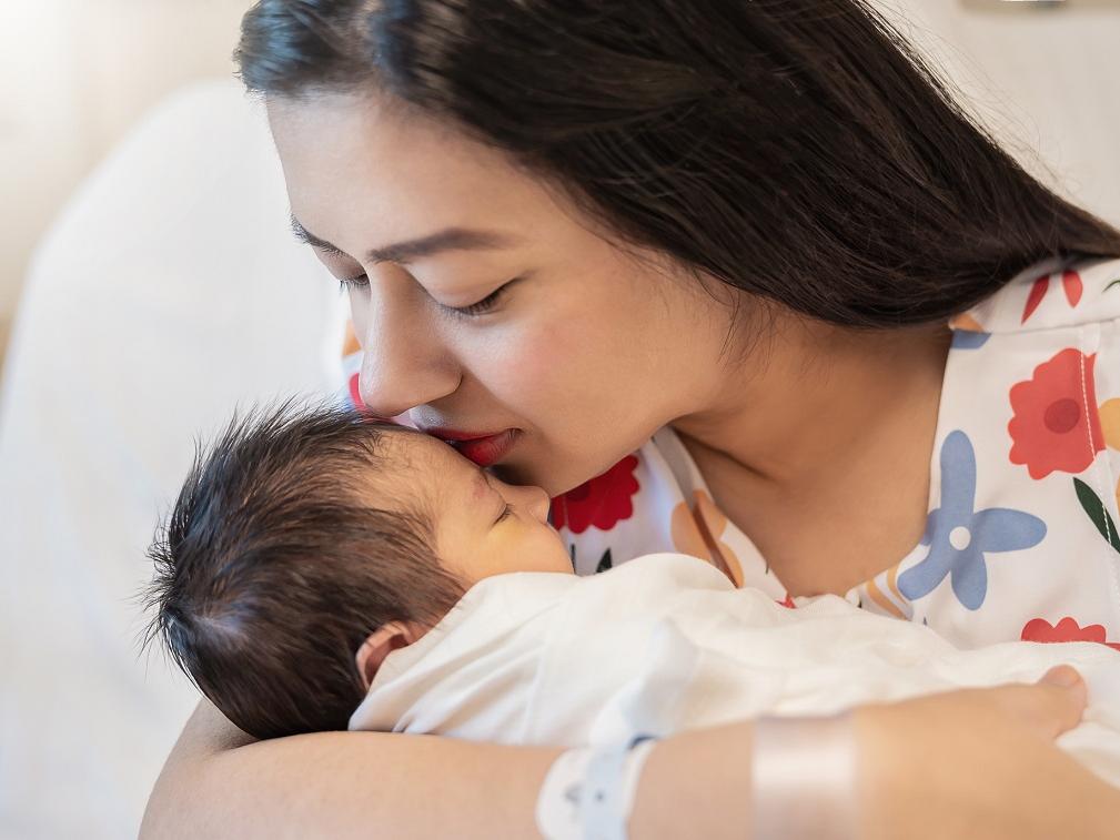 Close-up portrait of young mother holding newborn baby.