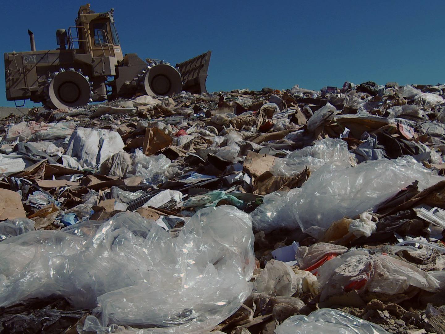 tractor in a landfill, filled with plastic bags