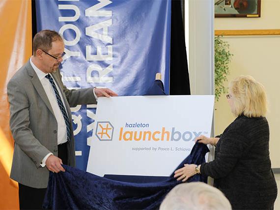 Penn State Hazleton Chancellor Gary Lawler, left, and Linda Schiavo unveil the logo for the Hazleton LaunchBox, which will be named after Linda's brother, the late Pasco L. Schiavo.