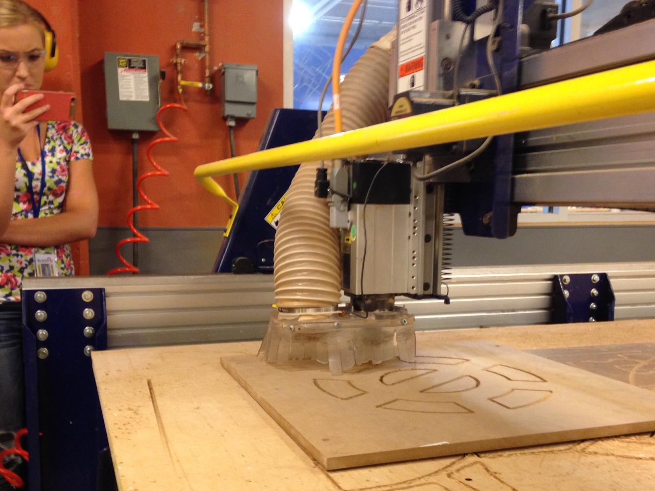 Engineering student Leah Berry records the ShopBot in action with her smart phone.