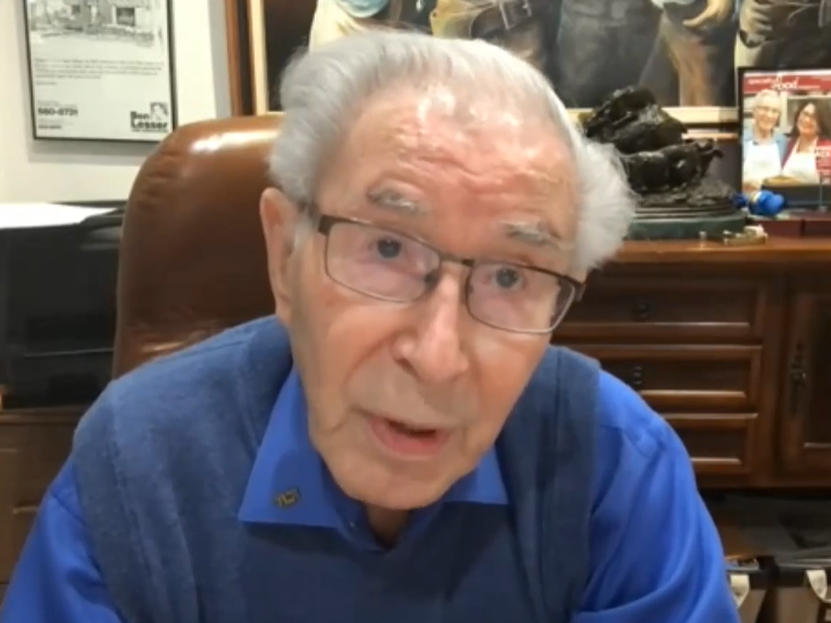 Man in a blue shirt and vest seated in a leather office chair.