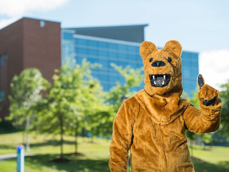 The Penn State Nittany Lion mascot poses in front of Burke Center at Penn State Behrend