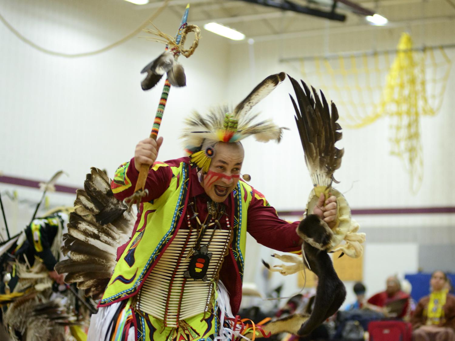 An American Indian dancer dressed in traditional regalia dances the "Duck and Dive" dance