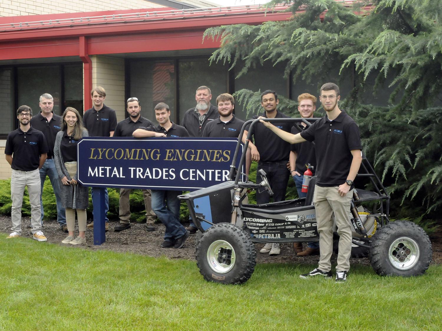Baja SAE Club members standing with an engine