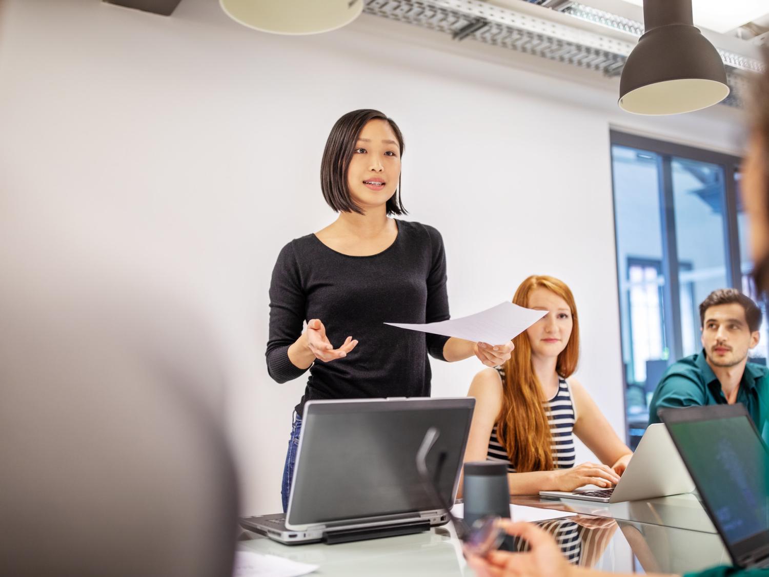 Female professional presenting in front of a group of peers. 