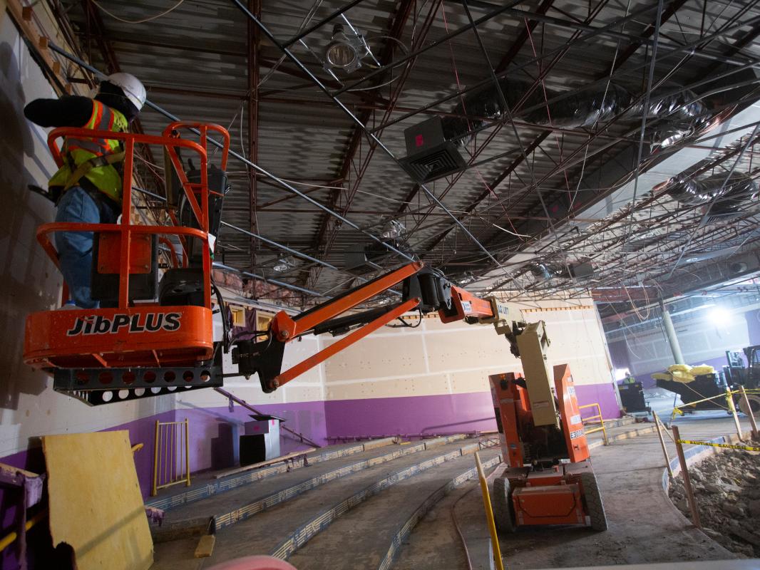 A person stands on a piece of construction equipment during a building demolition