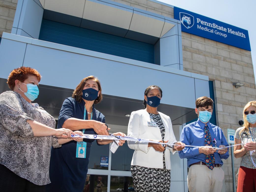 A group of officials participate in a ribbon cutting outside of a new medical facility 