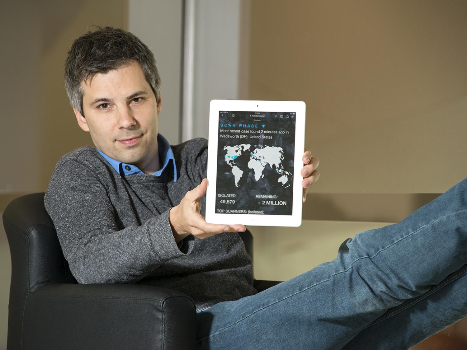 Marcel Salathé sitting with Moocdemic game on iPad screen