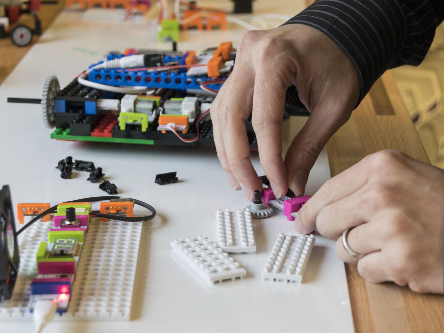 Close-up photo of two hands working with littleBits and legos on a table