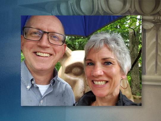 A man and a woman pose for a selfie with the Penn State lion statue in the background.