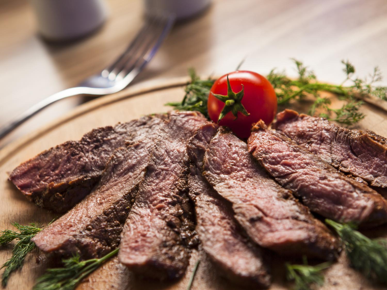 A plate of sliced beef garnished with a tomato