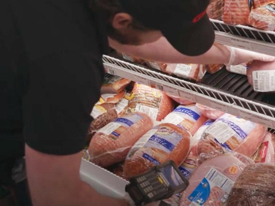 man filling meat case at grocery store