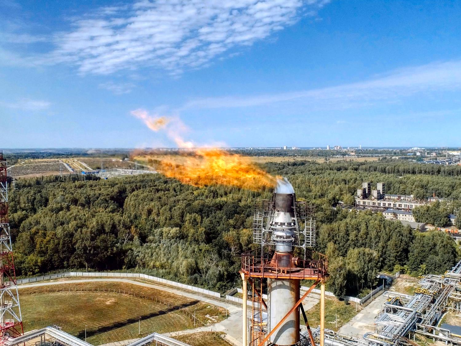 Tall gas pipe buring off methane with a visable flame